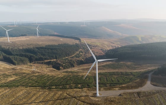 Aerial photo of a wind farm with several wind turbines located in a lush green landscape. Aerial photo of a wind farm with several wind turbines located in a lush green landscape.